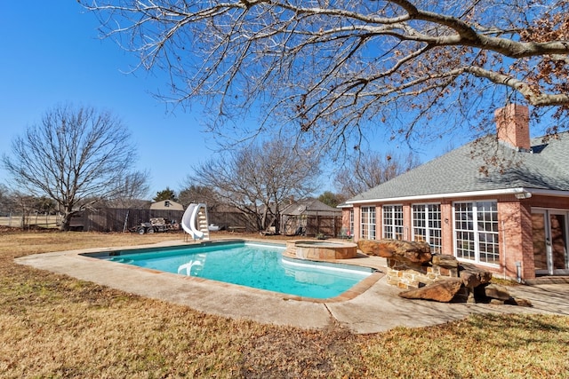 view of pool with an in ground hot tub, a water slide, and a lawn