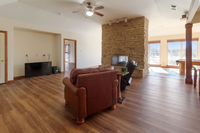 living room with rail lighting, ceiling fan, a fireplace, wood-type flooring, and ornate columns