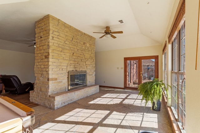 living room with a stone fireplace, a wealth of natural light, and ceiling fan