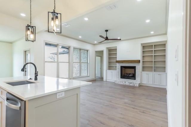 kitchen with sink, white cabinetry, crown molding, hanging light fixtures, and a kitchen island with sink