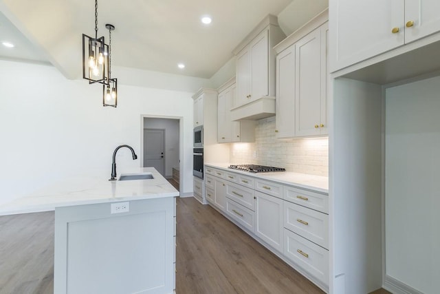 kitchen featuring decorative light fixtures, white cabinetry, sink, stainless steel appliances, and light stone countertops