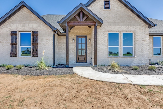 view of front of property with a shingled roof and brick siding