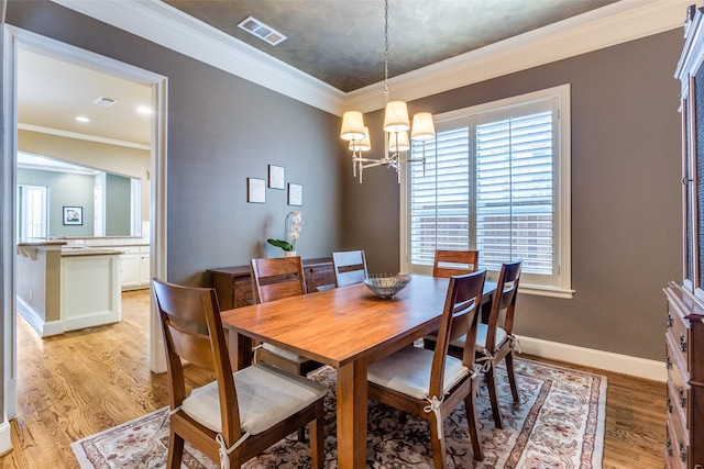 dining room with a notable chandelier, ornamental molding, and light hardwood / wood-style floors