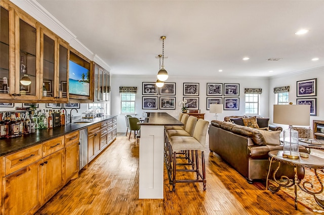 kitchen featuring sink, light hardwood / wood-style flooring, a kitchen breakfast bar, and hanging light fixtures