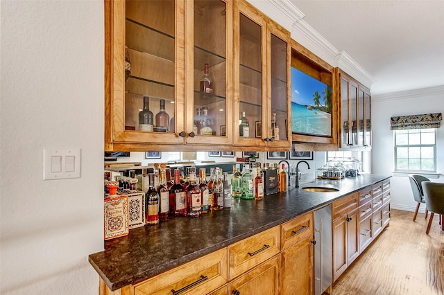 kitchen with ornamental molding, sink, light hardwood / wood-style floors, and dark stone counters