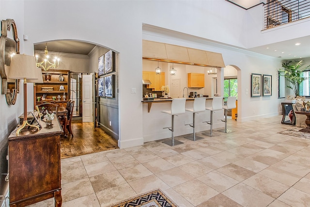 kitchen with ornamental molding, decorative light fixtures, a breakfast bar, and light brown cabinets