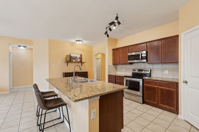 kitchen featuring appliances with stainless steel finishes, sink, a kitchen bar, decorative backsplash, and a center island with sink