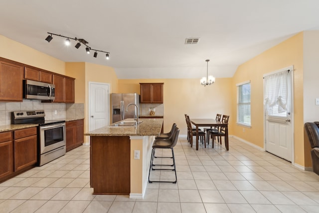 kitchen featuring appliances with stainless steel finishes, pendant lighting, sink, light tile patterned floors, and a center island with sink