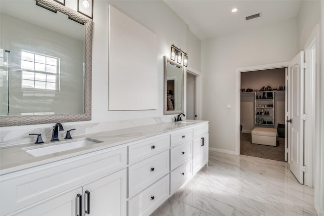 bathroom with marble finish floor, visible vents, a walk in closet, and a sink