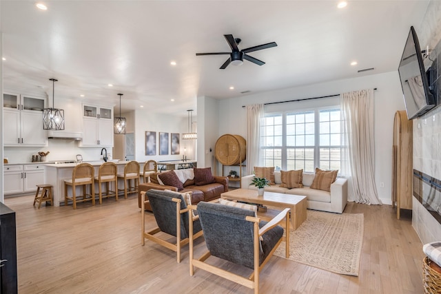 living area with recessed lighting, a ceiling fan, and light wood-style floors