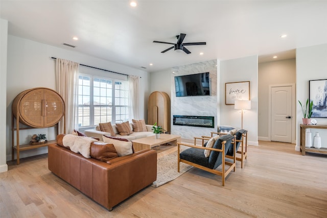 living area featuring a fireplace, recessed lighting, ceiling fan, light wood-type flooring, and baseboards