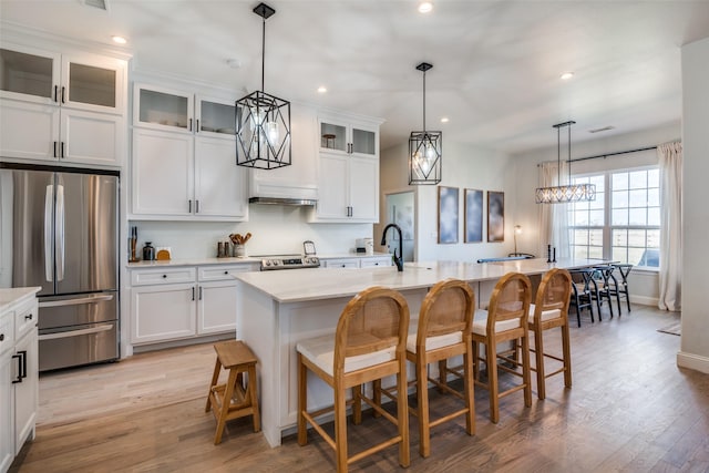 kitchen with appliances with stainless steel finishes, a breakfast bar, light countertops, and light wood-style floors