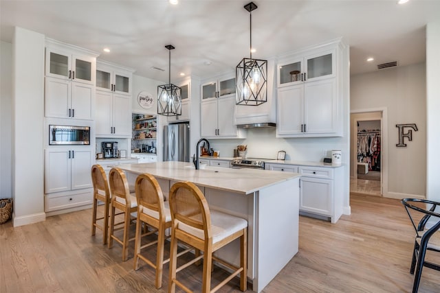 kitchen with appliances with stainless steel finishes, light wood-type flooring, visible vents, and a breakfast bar area