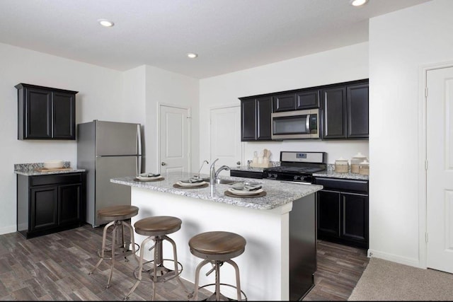 kitchen with a kitchen island with sink, a breakfast bar area, and appliances with stainless steel finishes