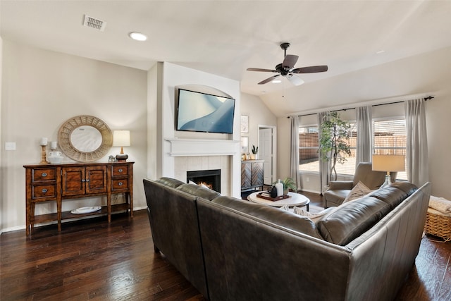 living room featuring a tiled fireplace, ceiling fan, lofted ceiling, and dark hardwood / wood-style flooring