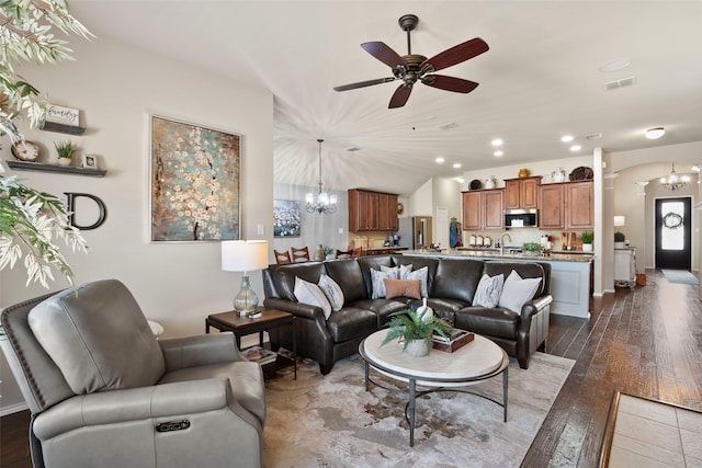 living room with sink, ceiling fan with notable chandelier, vaulted ceiling, and light wood-type flooring