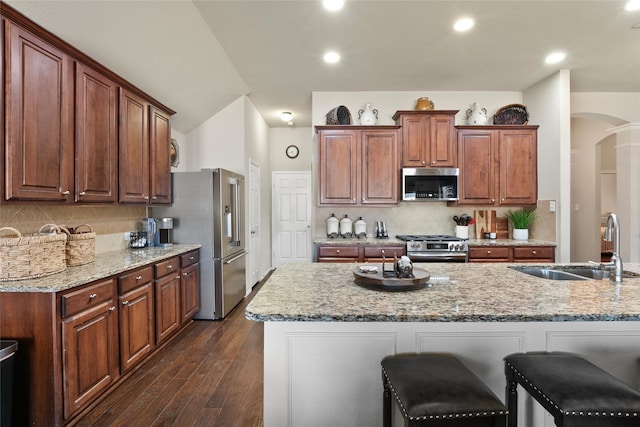 kitchen with sink, backsplash, stainless steel appliances, dark hardwood / wood-style floors, and light stone counters