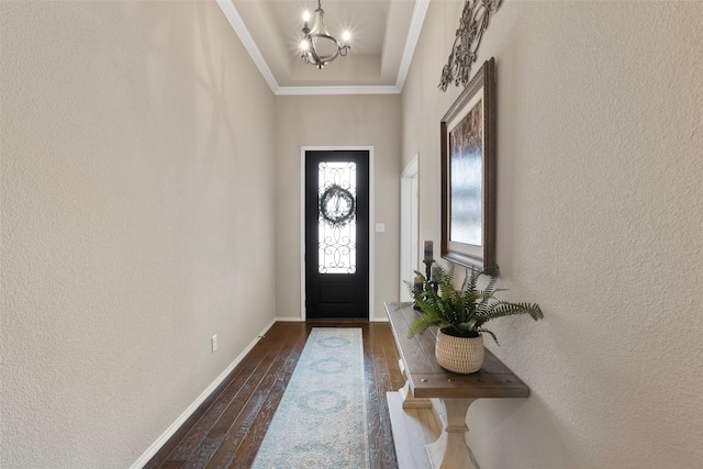 foyer entrance featuring an inviting chandelier, ornamental molding, and dark hardwood / wood-style floors