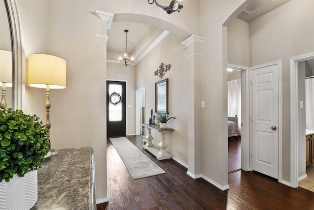 entryway with an inviting chandelier, dark hardwood / wood-style floors, and a high ceiling