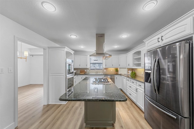 kitchen featuring appliances with stainless steel finishes, dark stone countertops, a center island, white cabinets, and island exhaust hood