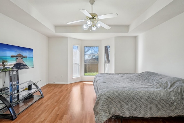 bedroom featuring hardwood / wood-style floors, ceiling fan, and a tray ceiling