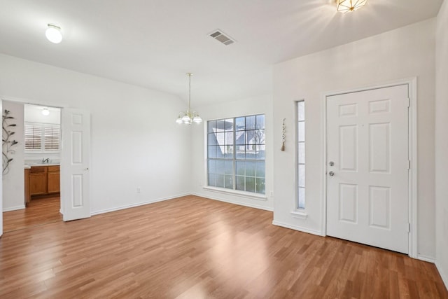 foyer with sink, an inviting chandelier, and light wood-type flooring