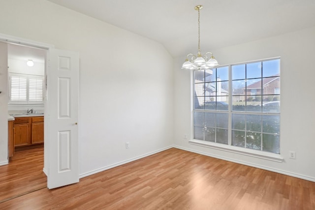 unfurnished dining area with an inviting chandelier, sink, light hardwood / wood-style flooring, and lofted ceiling