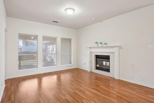 unfurnished living room featuring hardwood / wood-style flooring and a tile fireplace