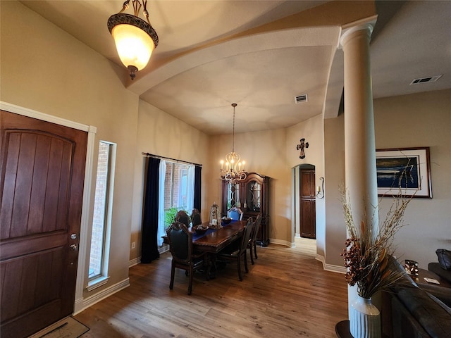 foyer featuring hardwood / wood-style flooring, a chandelier, and ornate columns