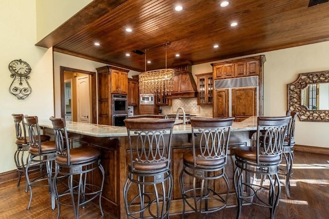 kitchen featuring a spacious island, built in appliances, a breakfast bar, and backsplash