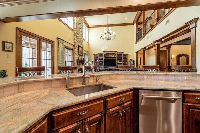 kitchen featuring pendant lighting, sink, dark brown cabinets, a high ceiling, and stainless steel dishwasher