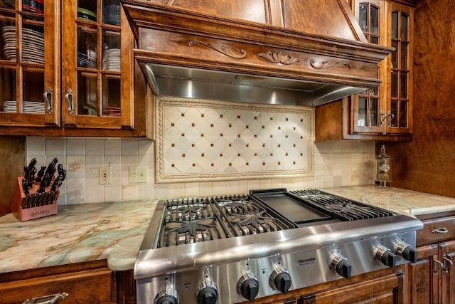 kitchen with tasteful backsplash, range, light stone counters, and wall chimney range hood