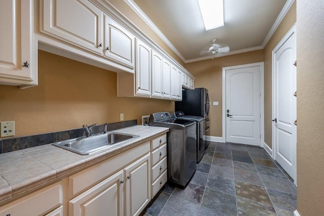 washroom featuring cabinets, crown molding, sink, and washing machine and clothes dryer