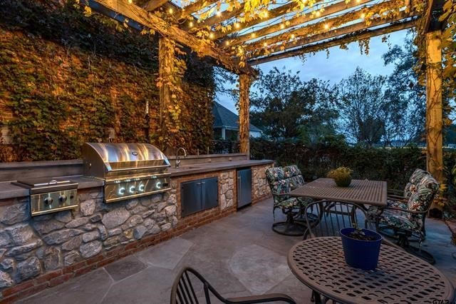 view of patio / terrace featuring exterior kitchen, sink, grilling area, and a pergola