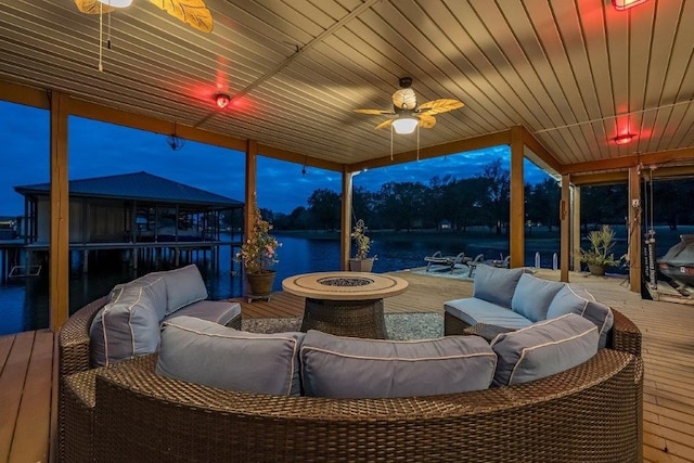 interior space with a water view, an outdoor living space with a fire pit, and ceiling fan