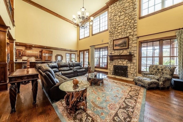 living room with ornamental molding, dark hardwood / wood-style floors, a stone fireplace, and a notable chandelier