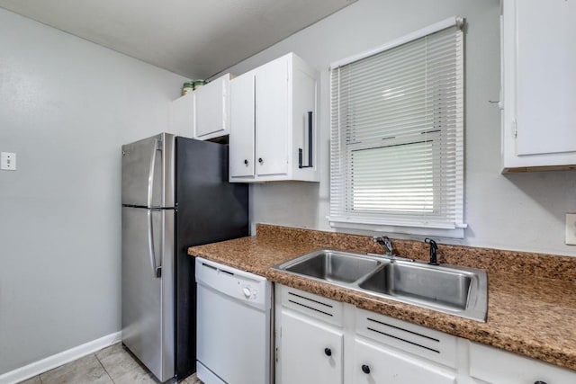 kitchen featuring sink, light tile patterned floors, stainless steel refrigerator, white dishwasher, and white cabinets