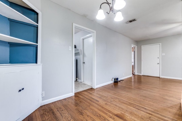 spare room featuring wood-type flooring and an inviting chandelier