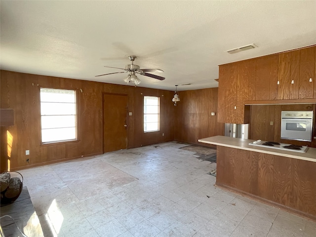 kitchen with wooden walls, white appliances, a healthy amount of sunlight, and decorative light fixtures