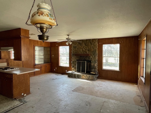 kitchen with plenty of natural light, kitchen peninsula, a fireplace, and wood walls