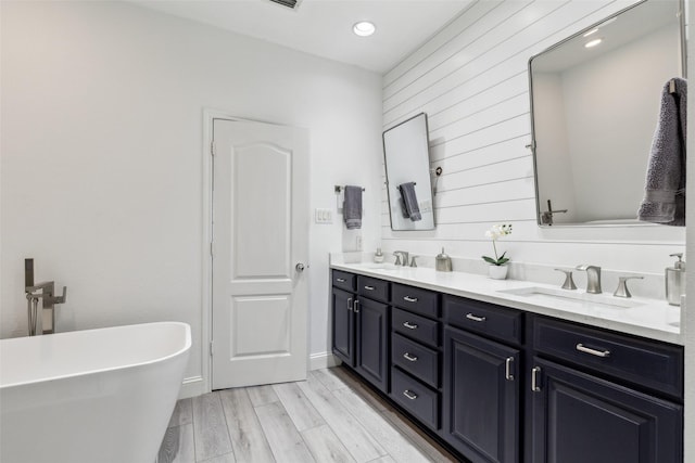 bathroom featuring vanity, a tub to relax in, hardwood / wood-style flooring, and wood walls