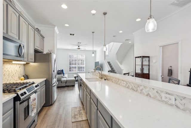 kitchen featuring pendant lighting, ornamental molding, appliances with stainless steel finishes, and gray cabinetry