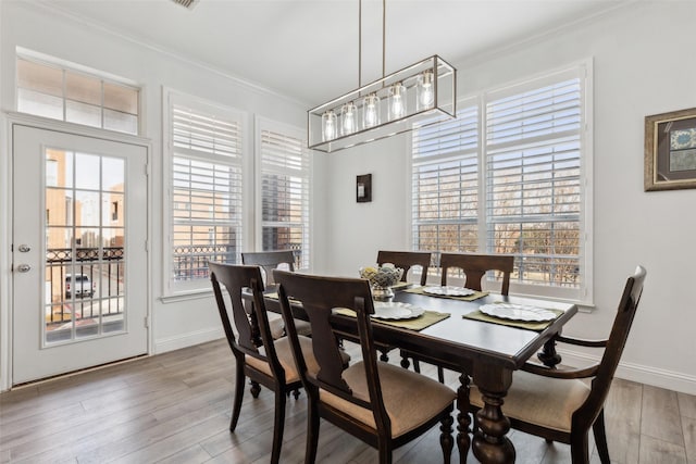 dining space featuring crown molding and light hardwood / wood-style flooring