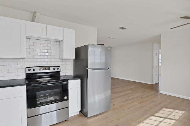 kitchen with appliances with stainless steel finishes, dark countertops, white cabinetry, and visible vents