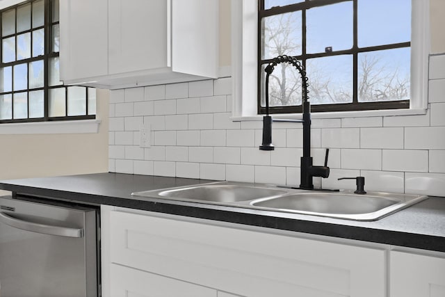 kitchen featuring dishwasher, white cabinetry, a sink, and backsplash