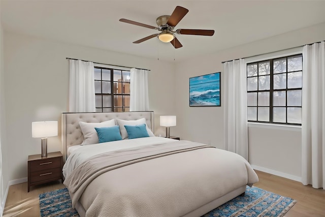 bedroom with baseboards, a ceiling fan, and light wood-style floors