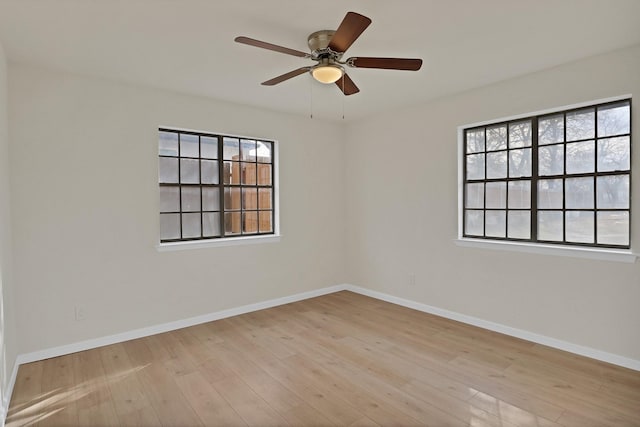unfurnished room featuring baseboards, ceiling fan, wood finished floors, and a healthy amount of sunlight
