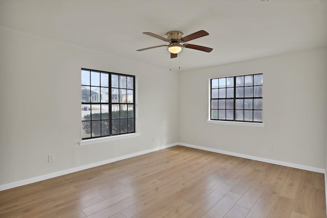 unfurnished room with a wealth of natural light, a ceiling fan, wood finished floors, and baseboards