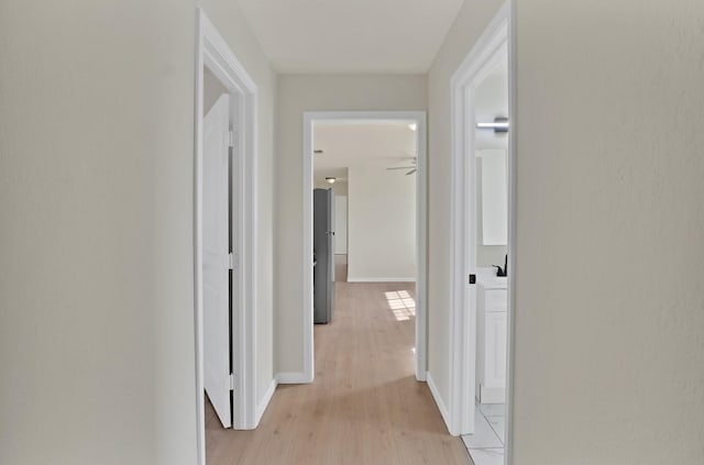 hallway featuring light wood finished floors and baseboards