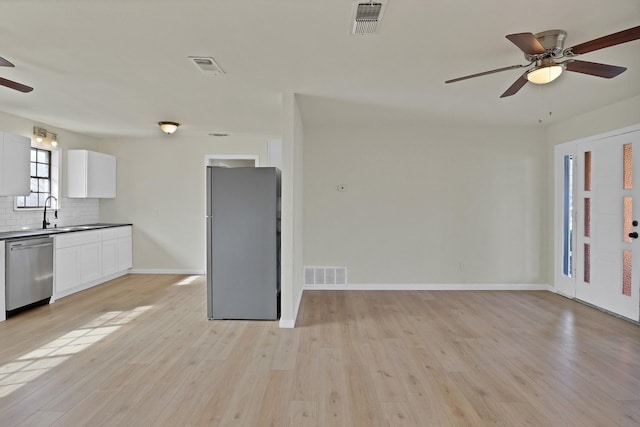 interior space with light wood-style flooring, a ceiling fan, and visible vents